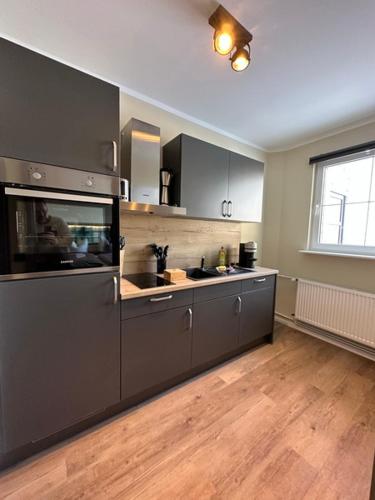 a kitchen with black cabinets and a wooden floor at Lieblingsquartier Sankt Andreasberg Studio 9 in Sankt Andreasberg