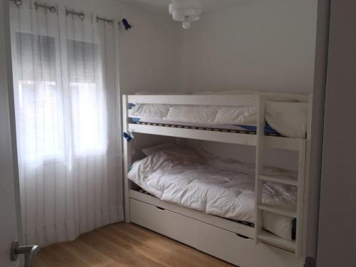 Ce lit superposé blanc se trouve dans un dortoir doté d'une fenêtre. dans l'établissement Bassin Arcachon Appt recent4 couchages petit jardin, à La Teste-de-Buch