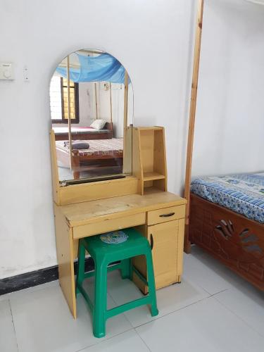 a wooden dressing table with a mirror and a stool at Balcony Bliss & Private Bath at Mamdalis in Ngambo