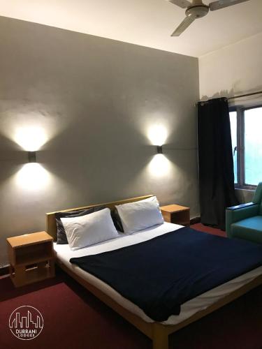 a bedroom with a bed and two lights on the wall at Durrani Lodges - G11 Islamabad in Islamabad