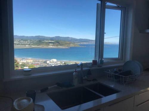 a kitchen sink with a view of the ocean at Views for day's in Lyall Bay in Wellington