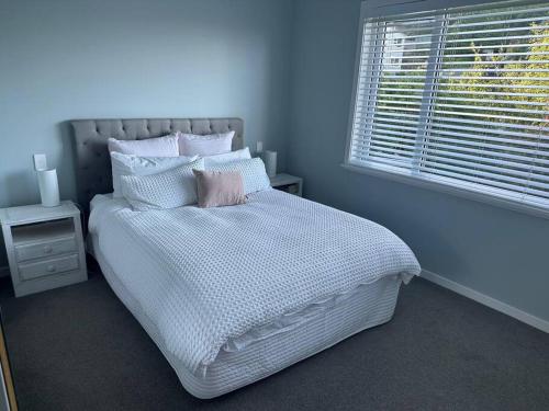 a bedroom with a white bed with a window at Views for day's in Lyall Bay in Wellington