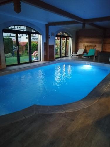 une grande piscine avec de l'eau bleue dans un immeuble dans l'établissement LES GRANGES DE JADIS ALSACE Bis, à Holtzwihr