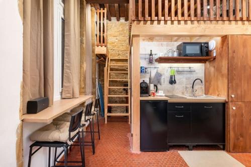 une cuisine avec un évier et un comptoir avec des tabourets dans l'établissement Le Cocon de Saint-Jean, à Lyon