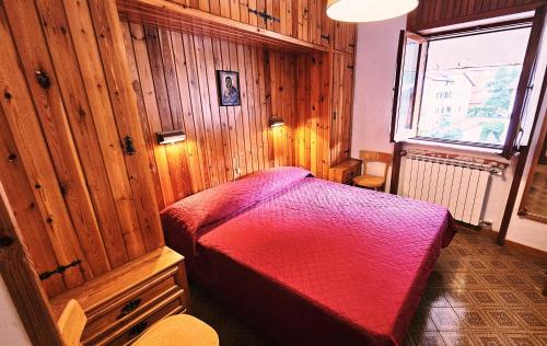 een slaapkamer met een rood bed in een houten kamer bij Armonia 13 - Pieno Centro in Roccaraso