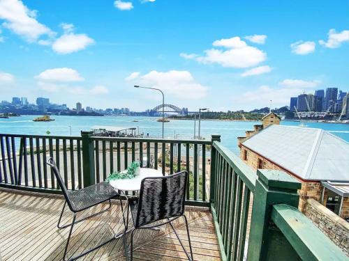 a table and chairs on a deck with a view of the water at Balmain Wharf l 2 Bedroom Apartment in Sydney