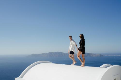a man and a woman standing on the edge of a boat at Santorini Princess Spa Hotel in Imerovigli