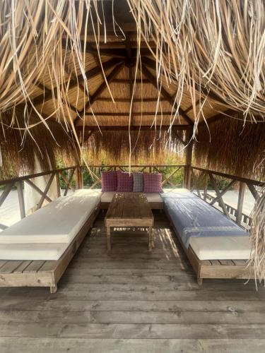 two beds and two tables in a straw hut at Hermes Penthouse Sea Sky & Mountains in Akanthou