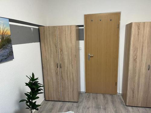 two wooden doors in an empty room with a plant at Monteurwohnung in Marl - Schiller - 1OGL in Marl
