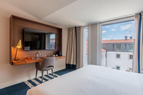 a hotel room with a bed and a desk and a window at Palácio do Governador - Lisbon Hotel & Spa in Lisbon