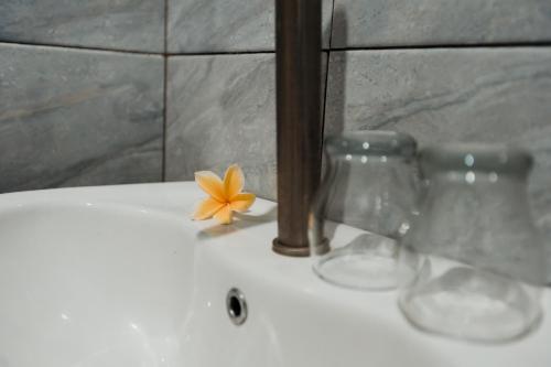 two wine glasses and a flower sitting on a sink at Kelating Dream Guest House in Krambitan