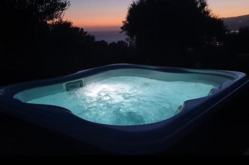 a jacuzzi tub with a sunset in the background at Casolare Cento Ulivi Luxury & Charme - Villa exclusive use in Ascea