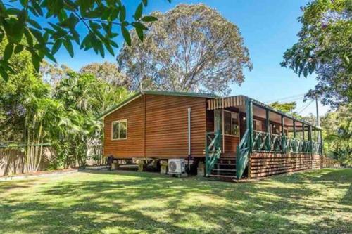 a wooden cabin in a field of grass with trees at NORTH BYRON BEACH HOUSE Surf Sun Sand in South Golden Beach
