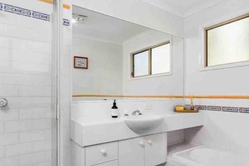 a white bathroom with a sink and a mirror at NORTH BYRON BEACH HOUSE Surf Sun Sand in South Golden Beach