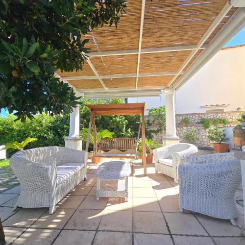 a patio with white wicker chairs and a pergola at La Spiga in Capri