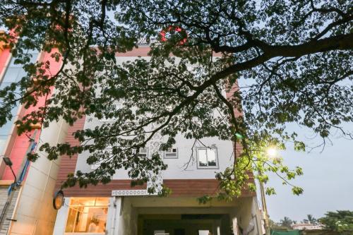 a white house with a tree in front of it at Hotel O IRA Sathyajyothi Comfort in Bengaluru