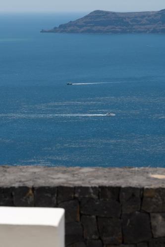 a boat in the water near the ocean at Santorini Princess Spa Hotel in Imerovigli
