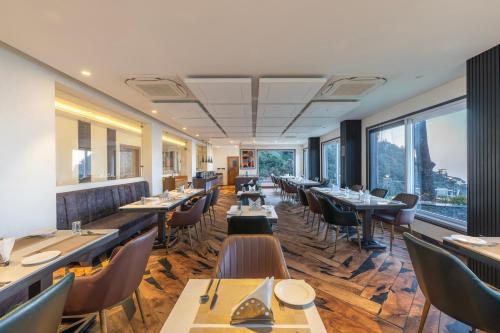 um restaurante com mesas e cadeiras e grandes janelas em Echor Baris Resort Mussoorie em Mussoorie