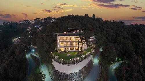 a large house on top of a hill next to a river at Echor Baris Resort Mussoorie in Mussoorie