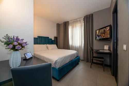 Pokój z łóżkiem i stołem z wazonem kwiatów w obiekcie Golden Hotel w mieście Neapol