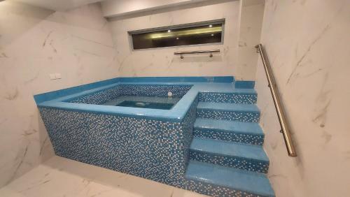 a bathroom with a blue tub with stairs in it at Ramada by Wyndham Murree Lower Topa Resort in Murree