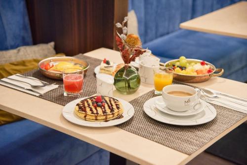 een tafel met een ontbijt van wafels en koffie en fruit bij Hotel Moon & Sun Porto in Porto