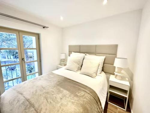 une chambre blanche avec un grand lit et une fenêtre dans l'établissement Saint Tropez High Standing 1, à Saint-Tropez