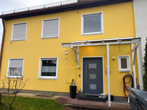 a yellow house with a front door at 1 Privatzimmer möbliert gut ausgestattet und gute Anbindung Bus Bahn in Hohenbrunn