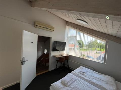 a bedroom with a bed and a window and a desk at Go-Sleep Bredehus in Bredsten