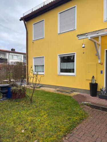 a yellow house with white windows and a yard at 1 Privatzimmer möbliert gut ausgestattet und gute Anbindung Bus Bahn in Hohenbrunn