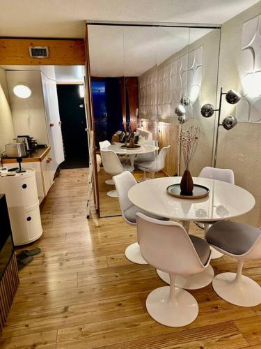 une chambre avec des tables et des chaises blanches et une cuisine dans l'établissement Magnifique Studio Arcs 2000, à Bourg-Saint-Maurice