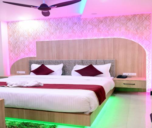 a bedroom with a large bed with pink lighting at Hotel Shankara Residency in Varanasi