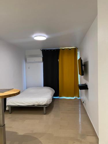 Cette chambre comprend un lit et un rideau jaune. dans l'établissement Studio Lumineux à 2min de là plage, à Nice