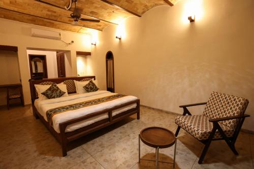 a bedroom with a bed and a chair at Le Casa Lion Resort A Premium Resort In Sasan Gir in Sasan Gir