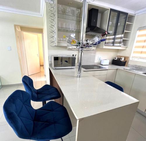 a kitchen with two blue chairs and a counter at ROBIES MANs CAVE in Alberton