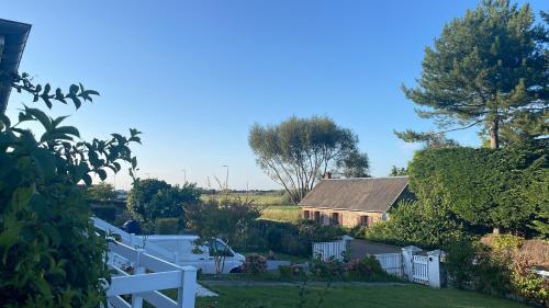 une maison avec une clôture blanche dans une cour dans l'établissement Maison Coco Quiberville sur Mer-groundfloor, à Quiberville