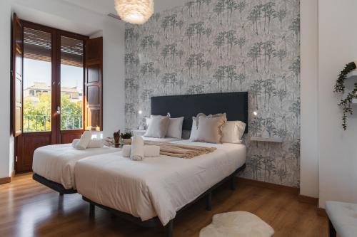 Un dormitorio con dos camas y una pared con papel pintado. en tuGuest Bib Rambla Aparments, en Granada