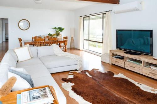 Una sala de estar con un sofá blanco y un televisor. en Salt bush cottage Peterborough, en Peterborough
