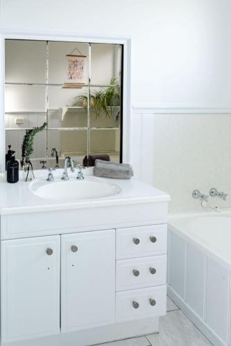 a white bathroom with a white sink and a tub at Salt bush cottage Peterborough in Peterborough