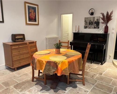 a dining room with a table and a piano at The Coach House in Saint-Côme-de-Fresné