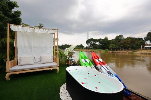 a boat with a chair and a bathtub on the side of a river at Mata villa มาตา วิลล่า in Chiang Mai