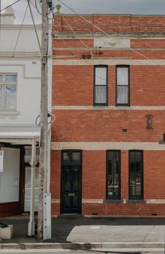 a red brick building with black doors on a street at Merchant on Malop - Luxe City Escape in Geelong
