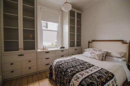 a bedroom with a bed and cabinets and a window at Merchant on Malop - Luxe City Escape in Geelong