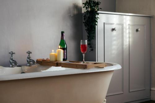 a bath tub with a bottle of wine and a glass at Character Cheltenham Georgian Town House in Gloucestershire