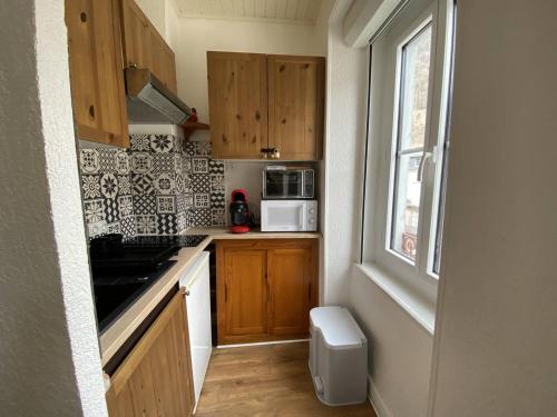 - une petite cuisine avec des placards en bois et un four micro-ondes blanc dans l'établissement Charmant T3 avec vue montagnes à Cauterets - FR-1-812-95, à Cauterets