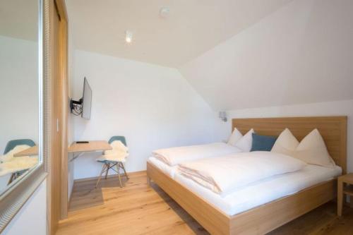 a bedroom with a bed with white sheets and a desk at Gasthof Grünwald in Sankt Daniel