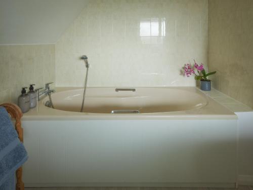 a white bath tub with flowers in a bathroom at Secluded Bolthole in Selmeston