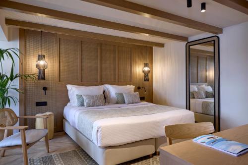 a bedroom with a large bed with a mirror at Mirabello Bay Luxury Resort in Agios Nikolaos
