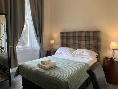 a bedroom with a bed with two towels on it at Bayswell Park Hotel in Dunbar