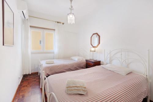 2 Betten in einem weißen Zimmer mit Spiegel in der Unterkunft Elegant Vintage House with barbecue in Cascais